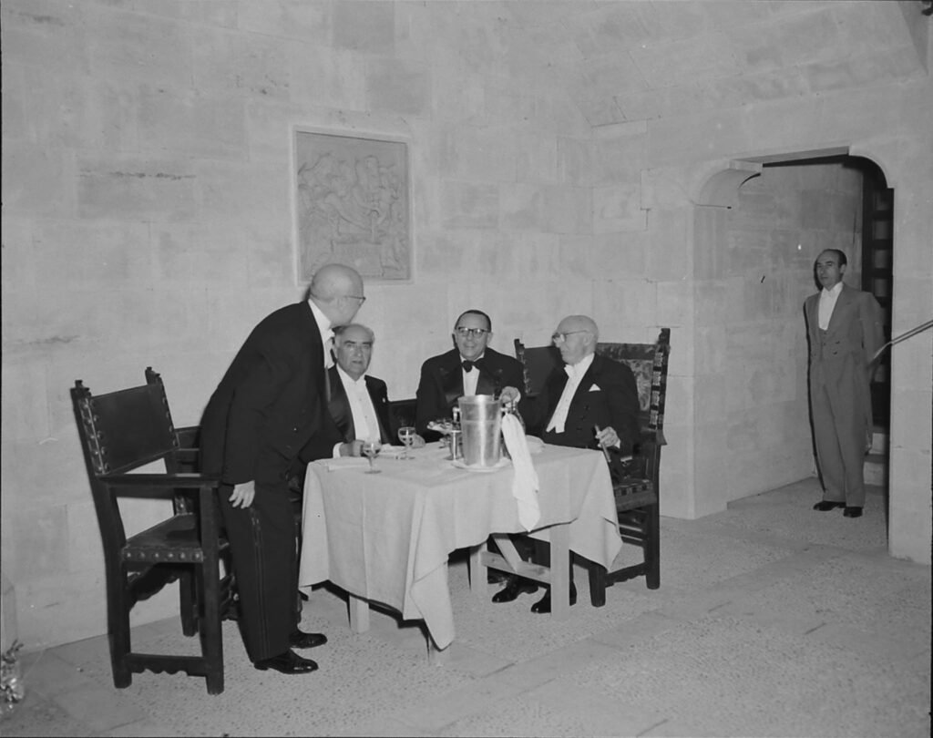 Juan March compartiendo mesa, bebiendo y fumando un puro en la puesta de largo (presentación en sociedad por alcanzar los 18 años) de su nieta Gloria March, junio de 1955, por Frank Scherschel